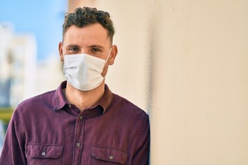 Young hispanic man wearing medical mask standing at the city.