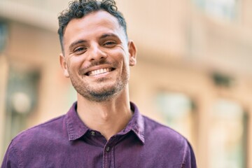 Young hispanic man smiling happy standing at the city.