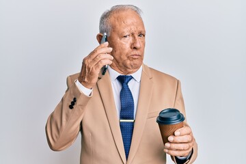 Naklejka premium Senior caucasian man talking on the smartphone and drinking a cup of coffee skeptic and nervous, frowning upset because of problem. negative person.