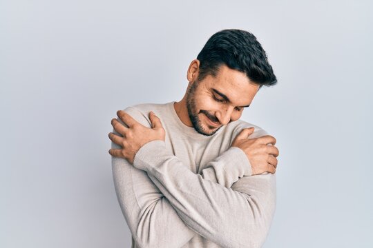 Young hispanic man wearing casual clothes hugging oneself happy and positive, smiling confident. self love and self care