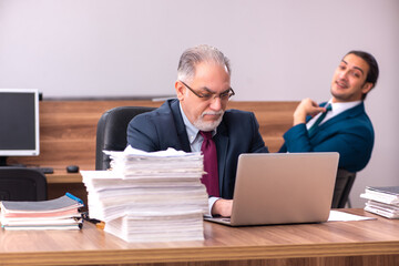 Old male employer and young male assistant in bullying concept