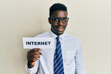 Handsome black man holding paper with internet word looking positive and happy standing and smiling with a confident smile showing teeth