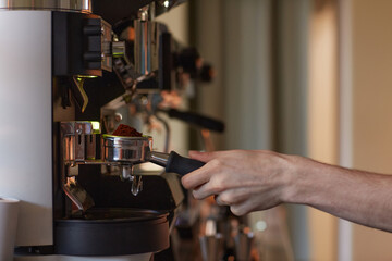 Side view closeup of male hand operating coffee machine while making fresh coffee in cafe, copy space