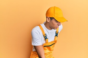 Young handsome african american man wearing handyman uniform over yellow background suffering of backache, touching back with hand, muscular pain