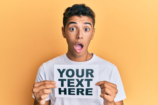 Young handsome african american man holding your text here banner afraid and shocked with surprise and amazed expression, fear and excited face.