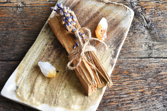 A top view image of several pieces of holy wood and healing crystals on a hand made pottery plate. 