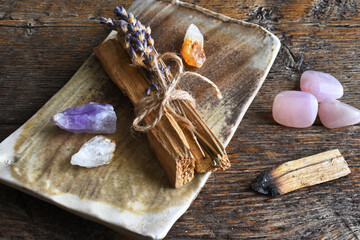 A top view image of several pieces of holy wood and healing crystals on a hand made pottery plate. 