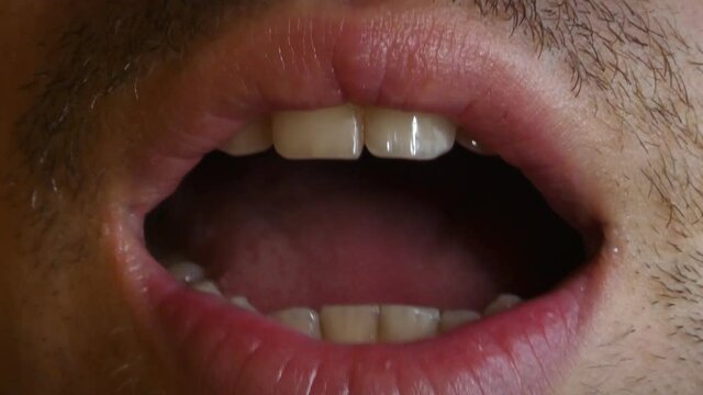 Detail of a young man's mouth, saying hi, talking, whispering, 4K detail