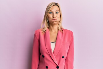 Middle age caucasian woman wearing business jacket puffing cheeks with funny face. mouth inflated with air, crazy expression.