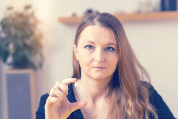 Woman is showing a test tube with solution of a self-testing kit closeup. Horizontally. 