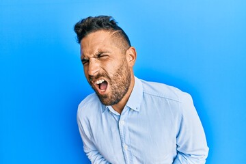 Handsome man with beard wearing casual clothes with hand on stomach because nausea, painful disease feeling unwell. ache concept.