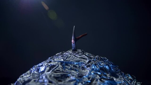 Rotates against a black background, a pickaxe in a stone, shining in the light and symbolizes the mining industry, as well as the work of geologists looking for minerals. Macro. Closeup
