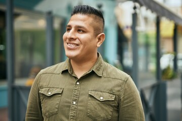 Young latin man smiling happy standing at the city.