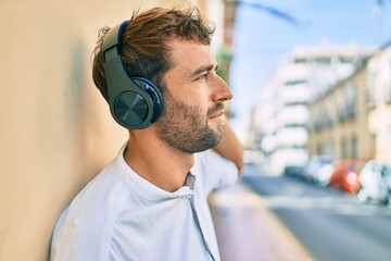 Handsome man with beard wearing headphones and enjoying listening to music outdoors