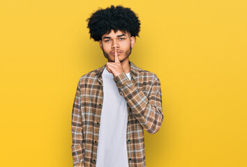 Fototapeta na wymiar Young african american man with afro hair wearing casual clothes asking to be quiet with finger on lips. silence and secret concept.