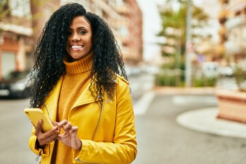 Middle age african american woman smiling happy using smartphone at the city.