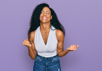 Middle age african american woman wearing casual style with sleeveless shirt very happy and excited doing winner gesture with arms raised, smiling and screaming for success. celebration concept.