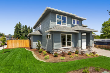 Exterior of new home on bright sunny day with blue sky. Features two car garage, front yard with...