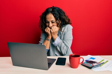 Beautiful middle age woman working at the office drinking a cup of coffee laughing and embarrassed giggle covering mouth with hands, gossip and scandal concept