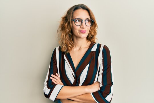 Young caucasian woman wearing business shirt and glasses smiling looking to the side and staring away thinking.
