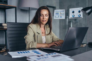 Woman working with documents and laptop sitting at her desk