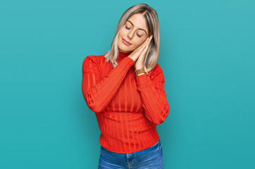 Beautiful blonde woman wearing casual clothes sleeping tired dreaming and posing with hands together while smiling with closed eyes.