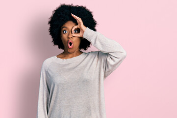 Young african american woman wearing casual clothes doing ok gesture shocked with surprised face, eye looking through fingers. unbelieving expression.