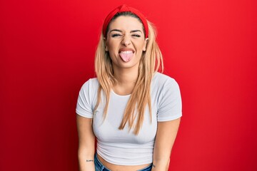 Young caucasian woman wearing casual white t shirt sticking tongue out happy with funny expression....