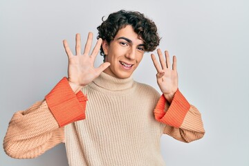 Hispanic young man wearing casual winter sweater showing and pointing up with fingers number nine...