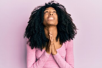 African american woman with afro hair wearing casual pink shirt begging and praying with hands...