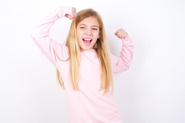Fototapeta premium Yes I am winner. Portrait of charming delighted and excited beautiful caucasian little girl wearing pink hoodie raising up fist in triumph and victory smiling achieving success grinning from delight.