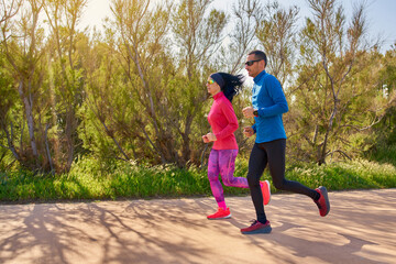 Obraz premium Couple running. Woman and man training together on nature in a nice and warm day. Bright colors and sunlight.