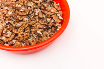 Peeled walnuts in red plastic plate on white background, isolated