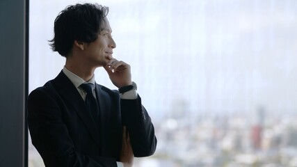 窓の外を眺めるビジネスマン