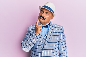 Mature middle east man with mustache wearing vintage and elegant fashion style thinking concentrated about doubt with finger on chin and looking up wondering