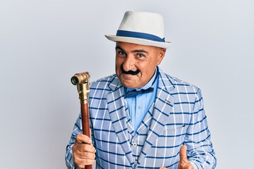 Mature middle east man with mustache wearing vintage and elegant fashion style winking looking at the camera with sexy expression, cheerful and happy face.