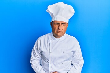 Mature middle east man wearing professional cook uniform and hat with hand on stomach because indigestion, painful illness feeling unwell. ache concept.