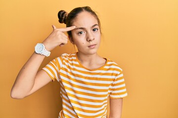 Beautiful brunette little girl wearing casual striped t shirt pointing unhappy to pimple on...