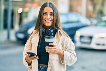 Young hispanic girl using smartphone and drinking take away coffee at the park. at the city.