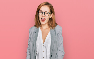 Young caucasian woman wearing business style and glasses winking looking at the camera with sexy expression, cheerful and happy face.