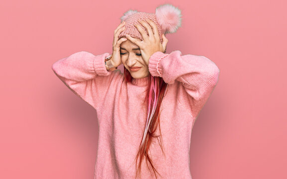 Young caucasian woman wearing casual clothes and wool cap suffering from headache desperate and stressed because pain and migraine. hands on head.