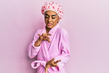 Hispanic man wearing make up wearing shower towel cap and bathrobe disgusted expression, displeased...