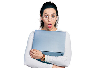 Fototapeta premium Young hispanic woman working using computer laptop afraid and shocked with surprise and amazed expression, fear and excited face.
