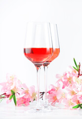 Rose wine glass with bottle on the white table and pink flowers. Rosado, rosato or blush wine tasting in wineshop, bar concept. Copy Space