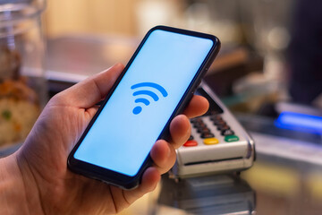 Customer is paying with smartphone in shop using NFC technology. against the background of the payment terminal.
