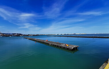 Obraz premium Pontili di legno sul mare con boe e vista sul porto in una giornata di sole