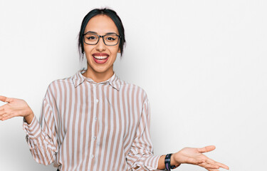 Young hispanic girl wearing casual clothes and glasses smiling cheerful with open arms as friendly...
