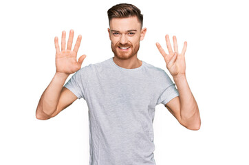 Young redhead man wearing casual grey t shirt showing and pointing up with fingers number nine while smiling confident and happy.