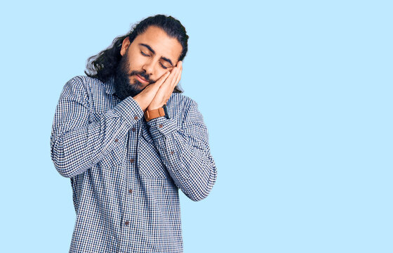 Young arab man wearing casual clothes sleeping tired dreaming and posing with hands together while smiling with closed eyes.