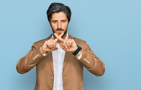 Young hispanic man wearing business clothes rejection expression crossing fingers doing negative sign